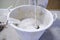 Close-up of white bucket plaster, the plasterer mixes the plaster in a large white bucket in low angle view