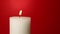 Close up white candle trembling flame over red