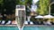 Close-up white champagne or prosecco glass against poolside at luxury resort hotel during vacation. Sparkling wine with