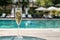 Close-up white champagne or prosecco glass against poolside at luxury resort hotel during vacation. Sparkling wine with