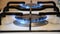 Close Up of White Cooking Stove with 2 Gas Burners, Blue Gas Burning on Both, Focus Changing from One Burner to Another