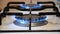 Close Up White Cooking Stove with Blue Fire on a Burner Switching Off