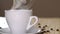 Close up of a white cup of evaporating coffee on table near roasted beans