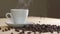 Close up of white cup of evaporating coffee on table near roasted beans. Slowly