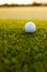 Close-up of white golf ball on lush grassy land at golf course during sunset, copy space