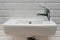 Close-up of white mini washbasin in the toilet with open chrome faucet washbasin