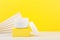 Close up of white opened cosmetic jar on yellow podium against yellow background with copy space