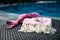 Close-up of a white and pink Turkish peshtemal / towel, pink bikini top and white seashells on rattan lounger.