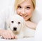 Close up of white puppy lying on the sofa with woman