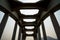 Close-up of a white railroad bridge looking up from the inside against white and blue sky background.