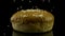 Close up of white sesame seeds falling down to the fresh burger bun isolated on black background, food and preparation