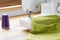 Close-up of a white sewing machine stitching a purple thread on a green fabric in a crafts room interior. Real photo.