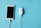 Close up white Smartphone Plug In with Charger Adapter on Blue Background