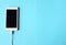 Close up white Smartphone Plug In with Charger Adapter on Blue Background