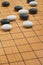 Close up the white stone and black stone of Go board game or Chinese, Japanese classic board game, grid line on wooden board,
