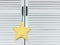 A close-up of a white-yellow soft star toy hangs on the handle of a white cabinet-screen
