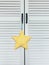 A close-up of a white-yellow soft star toy hangs on the handle of a white cabinet-screen