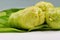 Close-up of whole Noni fruits, Morinda citrifolia, on leaf, against white background