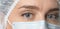 Close up widely opened eyes of doctor. Female doctor in protective mask with beautiful eyes close up.