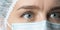 Close up widely opened eyes of doctor. Female doctor in protective mask with beautiful eyes close up.