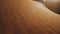 Close-up of wind blows sand in the desert of sand dunes in the Sahara desert at sunset, sun bunnies into camera, 4k