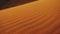 Close-up of wind blows sand in the desert of sand dunes in the Sahara desert at sunset, sun bunnies into camera, 4k