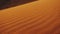 Close-up of wind blows sand in the desert of sand dunes in the Sahara desert at sunset, sun bunnies into camera, full hd