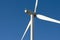 Close up of a wind farm turbine against a clear blue sky.