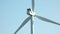 Close up of wind turbine spinning on blue sky background.