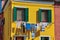 Close-up of windows on colorful walls and clothes hanging on, in Burano.