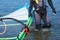 Close up of windsurfer in wetsuit holding windsurf sail in shallow water