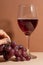 Close-up of the wineglass with red wine and bunch of grape. Girl gingers touch the grape. Food and drink concept