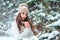 Close up winter portrait of dreamy young woman walking in snowy forest