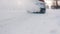 Close up on the winter tires of a moving car. Frozen vehicle driving on the snow covered road