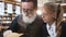 Close up of wise expirienced old grandpa reading interesting book with his smiling teen granddaughter in the library