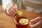 Close up of woman adding ginger to tea with lemon