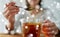 Close up of woman adding honey to tea with lemon