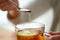 Close up of woman adding honey to tea with lemon