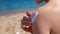 Close up of woman applying sunscreen to shoulder on tropical beach