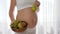 Close-up woman with baby in belly holds pear and fruits on dish