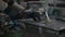 Close up of woman blacksmith welder welding two pieces of metal in her workshop helping herself with various tools -