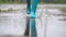 Close-up of woman in blue rubber boots jumping on the puddle