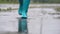Close-up of woman in blue rubber boots jumping on the puddle