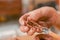 Close up of woman ceramist hands cleanning the tool after working on sculpture on wooden table in workshop, in a blurred