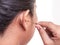 Close up woman cleaning her ear by using metal stick isolated on