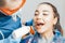 Close up of woman dentist in blue uniform holding curing lamp