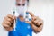 Close up woman doctor holding syringe and bottle of vaccine ready for injection to patient people in medical mask. Covid-19 or