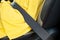 Close up of woman driver in yellow summer dress wearing seatbelt driving a car