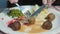 Close-up of a woman eating lunch, cutting meatballs into plates with a knife and dipping them in sweet sauce.