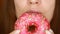 Close-up woman eating a pink donut , delicious, sweet, sweet tooth. Diet. Dieting. Female mouth bites a dessert.